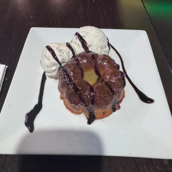 JamaGrille dessert with a chocolate-covered bundt cake and two scoops of ice cream drizzled with chocolate.
